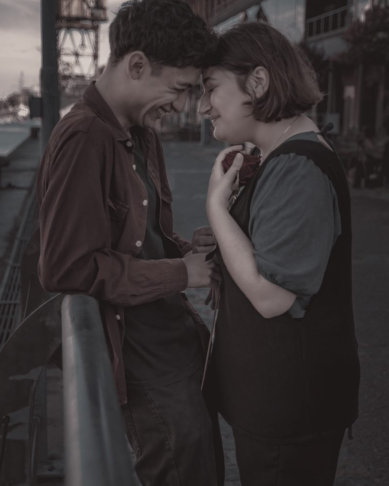 A couple resting their foreheads together on a quiet street