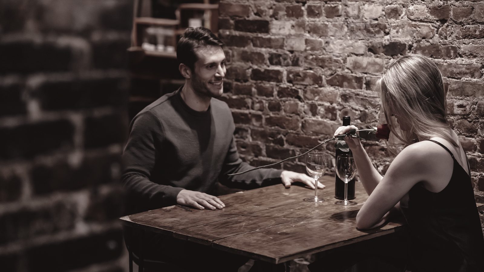 Two people talking over a small table in a candlelit room