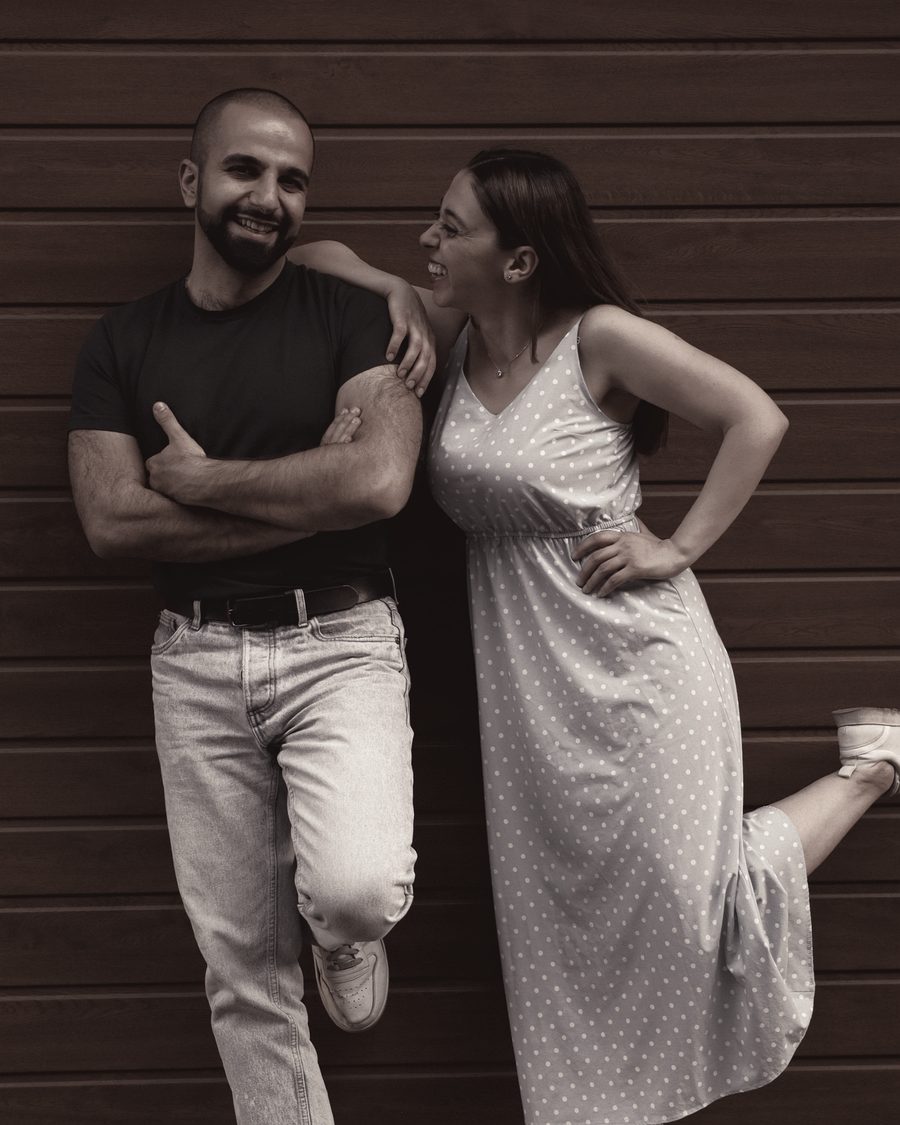 A couple leaning against a timber wall, laughing together